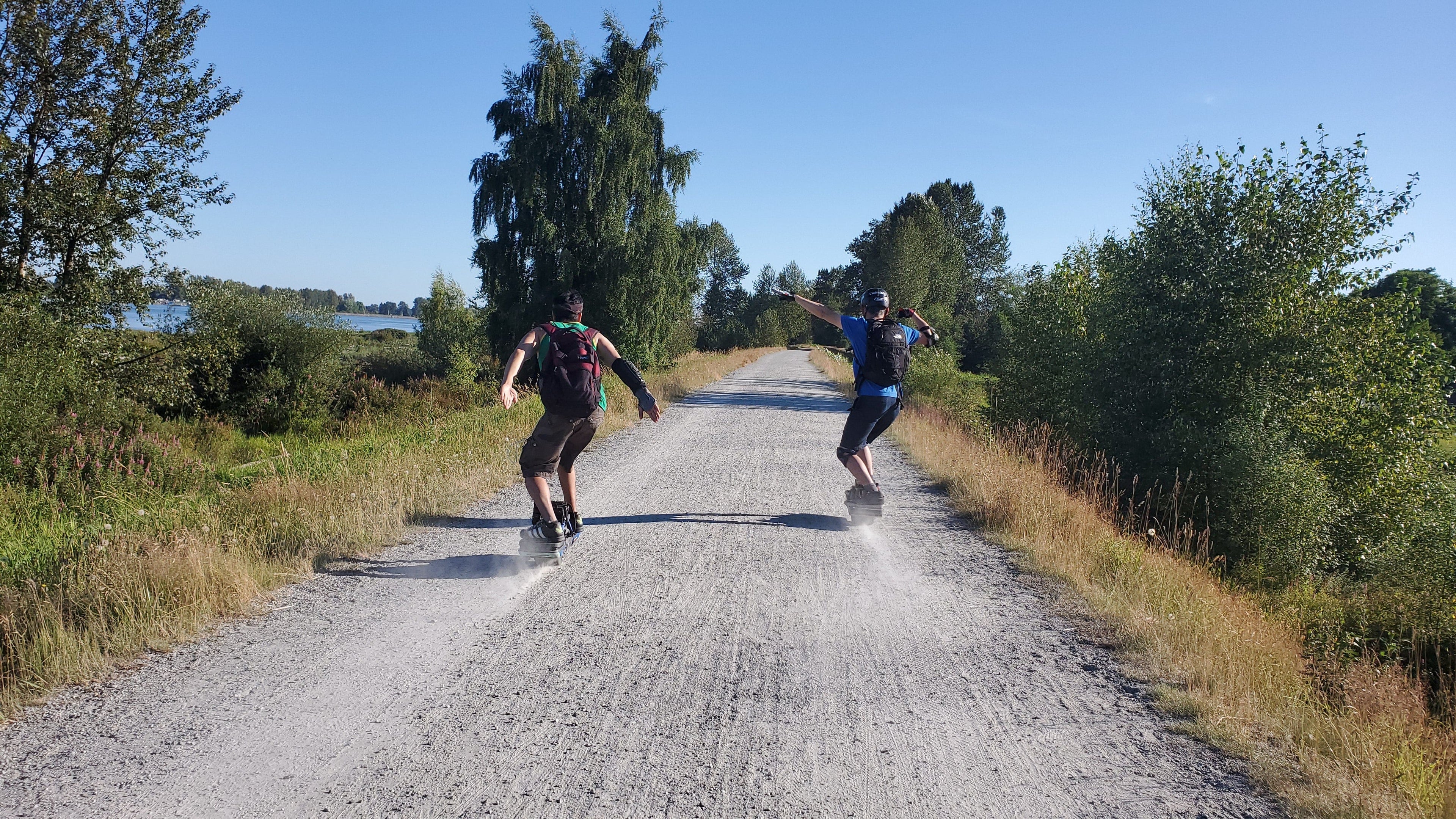 two men riding onewheel on a gravel trail
